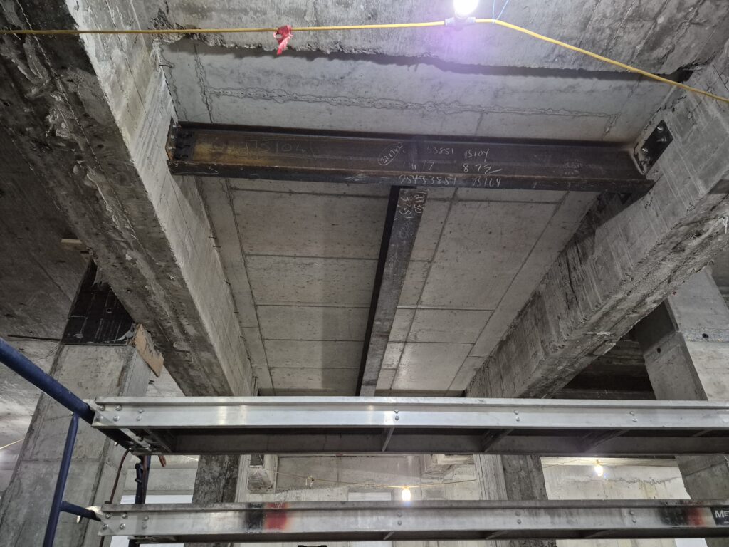 Steel I-beams installed beneath a concrete slab during structural retrofit